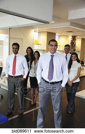 Stock Image - Smiling Hispanic business people standing together in office. Fotosearch