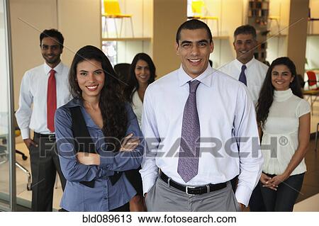 Stock Image - Smiling Hispanic business people standing together in office. Fotosearch