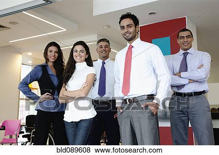 Stock Photo - Smiling Hispanic business people standing together in office. Fotosearch