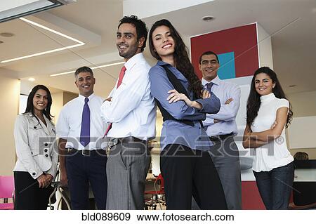 Stock Photo - Smiling Hispanic business people standing together in office. Fotosearch