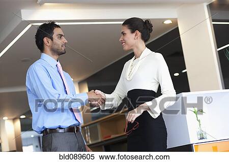 Stock Photography - Smiling Hispanic business people shaking hands in office. Fotosearch