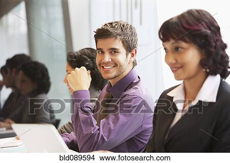 Picture - Smiling Hispanic businessman in office with co-workers. Fotosearch