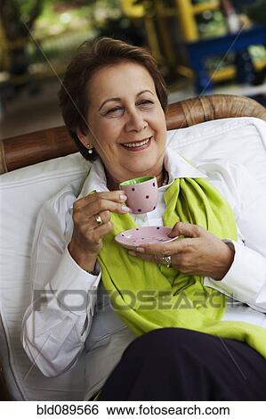 Smiling Hispanic woman drinking coffee View Large Photo Image Stock Photograph - Smiling Hispanic woman drinking coffee. Fotosearch