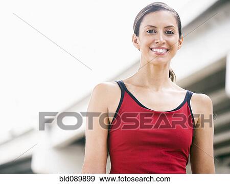 Stock Photo - Smiling Hispanic woman standing in urban area. Fotosearch