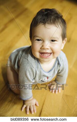 Stock Photograph - Smiling mixed race boy crawling on floor. Fotosearch