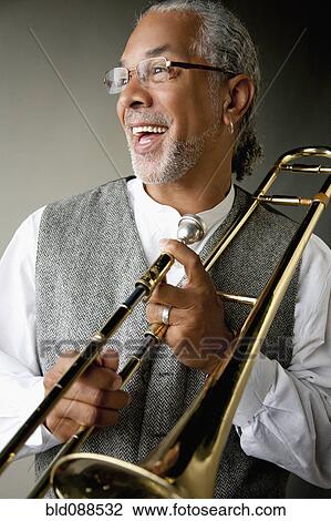 Stock Image - Smiling musician holding trombone. Fotosearch