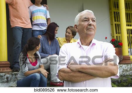 Stock Photograph - Stern Hispanic man with family in background. Fotosearch