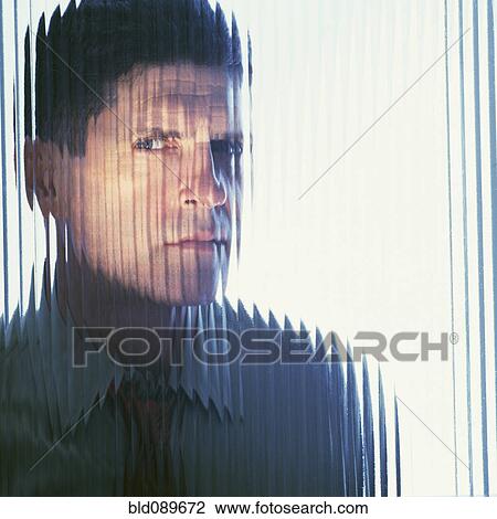 Stock Image - Suspicious businessman looking through glass wall. Fotosearch