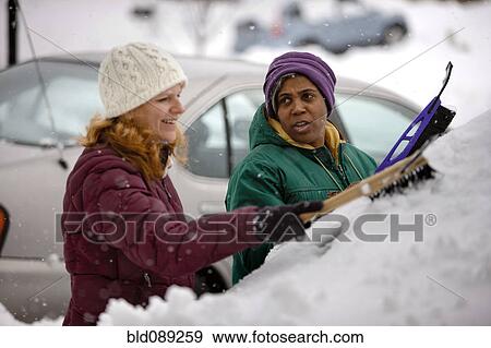 Stock Photo - Two women scraping snow from windshield. Fotosearch