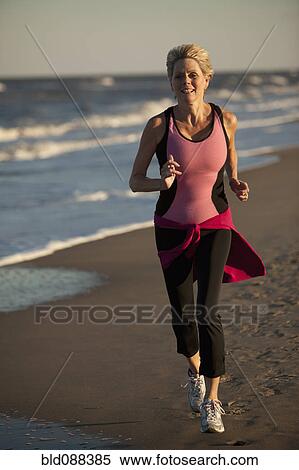 Stock Photography - Woman running on beach. Fotosearch