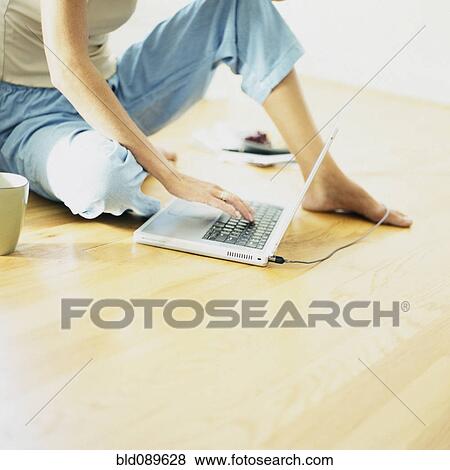 Stock Photo - Woman using laptop on floor. Fotosearch