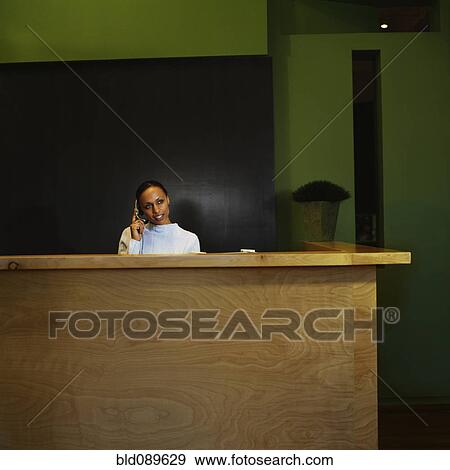 Stock Photo - Woman working at reception desk in office. Fotosearch
