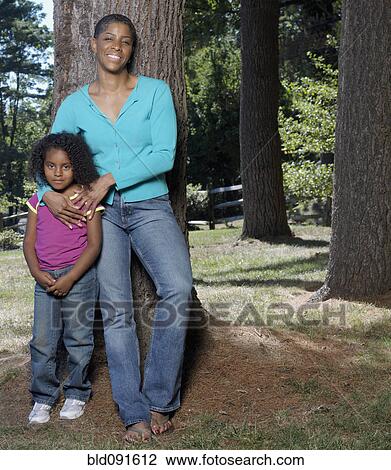 Stock Image - African American mother hugging daughter in park. Fotosearch