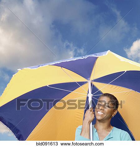 Stock Image - African American woman holding umbrella. Fotosearch