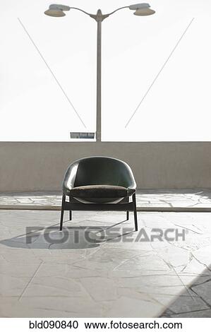 Stock Image - Armchair sitting on rooftop patio. Fotosearch