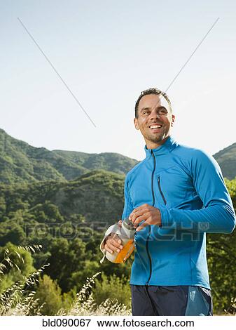 Stock Photo - Athletic mixed race man drinking water outdoors. Fotosearch