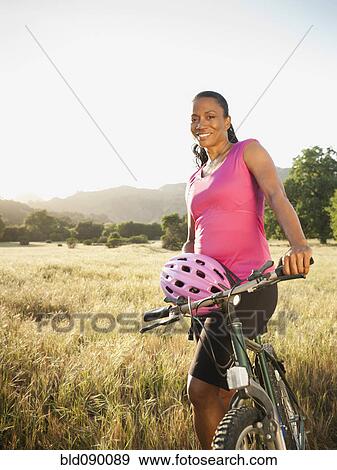 Stock Photo - Black biker standing with mountain bike. Fotosearch