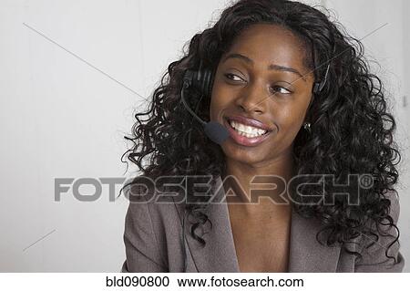 Stock Image - Black businesswoman talking on headset. Fotosearch