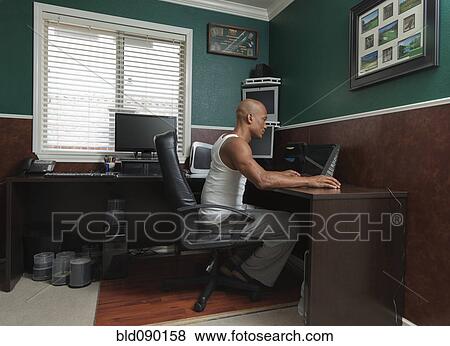 Black man working at desk in home office View Large Photo Image Stock Photo - Black man working at desk in home office. Fotosearch