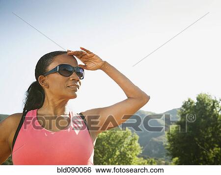 Stock Photograph - Black woman in sunglasses shielding eyes. Fotosearch
