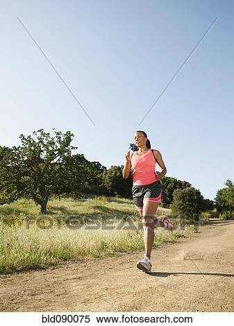 Stock Photography - Black woman running on remote trail. Fotosearch