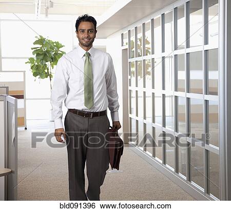 Stock Photograph - Businessman carrying briefcase in office. Fotosearch