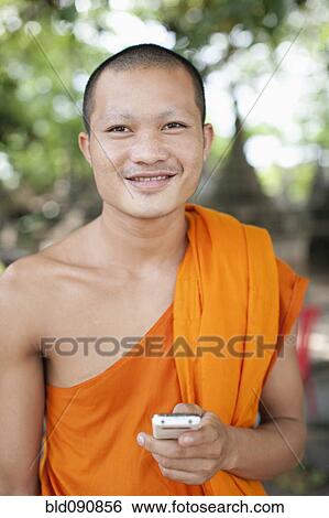 Stock Photograph - Cambodian monk text messaging on cell phone. Fotosearch