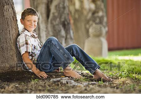 Caucasian boy leaning against tree trunk View Large Photo Image Stock Photography - Caucasian boy leaning against tree trunk. Fotosearch