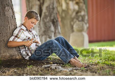 Picture - Caucasian boy whittling stick. Fotosearch