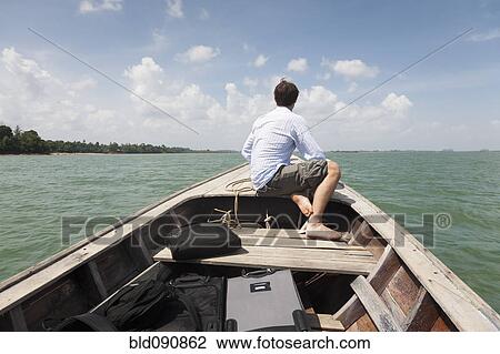 Stock Image - Caucasian businessman riding in boat. Fotosearch