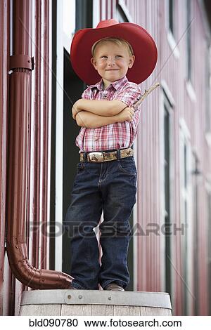 Stock Image - Caucasian cowboy standing on barrel. Fotosearch