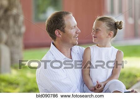 Stock Photograph - Caucasian father and daughter sitting together. Fotosearch