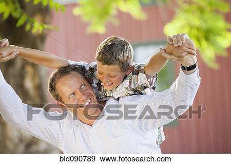 Stock Photo - Caucasian father carrying son on his shoulders. Fotosearch