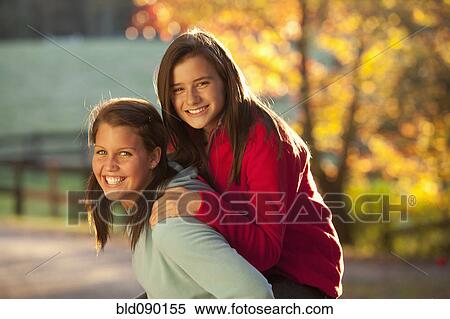 Caucasian girl carrying friend on her back View Large Photo Image Stock Photography - Caucasian girl carrying friend on her back. Fotosearch