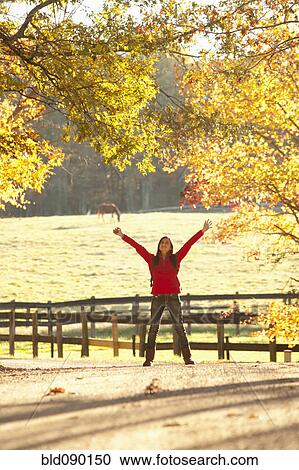 Stock Image - Caucasian girl standing with arms outstretched in countryside. Fotosearch