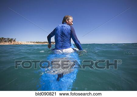 Stock Image - Caucasian man floating on surfboard. Fotosearch