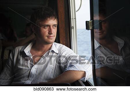 Stock Image - Caucasian man riding in boat. Fotosearch