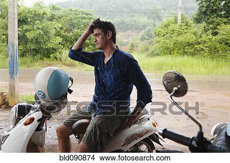 Picture - Caucasian man sitting on scooter. Fotosearch