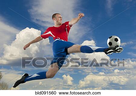 Caucasian soccer player jumping in mid-air kicking ball View Large Photo Image Stock Image - Caucasian soccer player jumping in mid-air kicking ball. Fotosearch