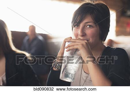 Stock Image - Caucasian teenager drinking water in restaurant. Fotosearch