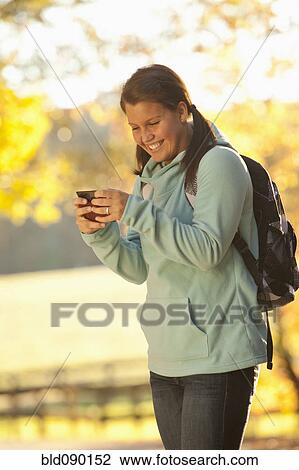 Stock Image - Caucasian teenager using cell phone outdoors. Fotosearch
