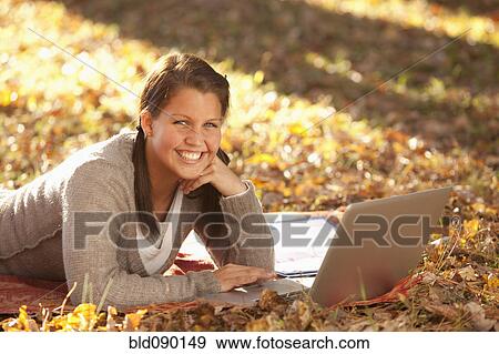 Caucasian teenager using laptop on ground View Large Photo Image Stock Photo - Caucasian teenager using laptop on ground. Fotosearch