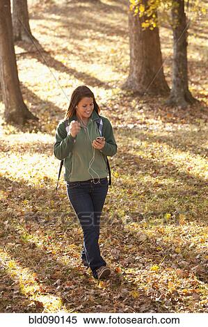 Stock Photography - Caucasian teenager with mp3 player walking in forest. Fotosearch