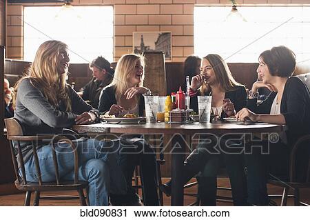 Stock Image - Caucasian teenagers eating together in restaurant. Fotosearch