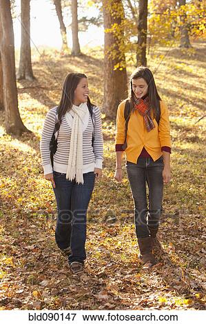 Stock Photo - Caucasian teenagers walking together in forest. Fotosearch