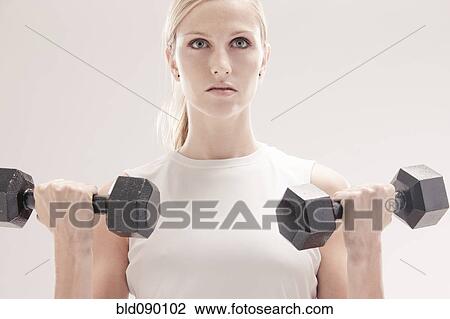 Stock Image - Caucasian woman exercising with dumbbells. Fotosearch