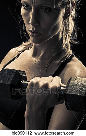 Stock Image - Caucasian woman exercising with dumbbells. Fotosearch