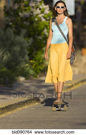 Picture - Caucasian woman skateboarding on street. Fotosearch