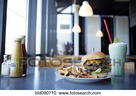 Stock Image - Cheeseburger, french fries and milkshake in diner. Fotosearch