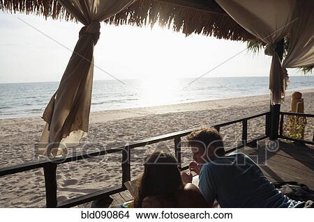 Couple laying on porch enjoying beach and ocean View Large Photo Image Picture - Couple laying on porch enjoying beach and ocean. Fotosearch